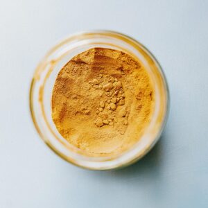 "Pure organic turmeric powder in wooden bowl – natural spice rich in curcumin for cooking and health benefits"
